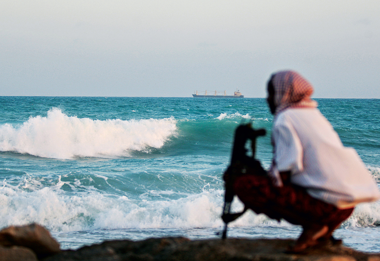 Observado por um pirata somali, um cargueiro grego ancora em Hobyo, nordeste da Somália. Foto: AFP